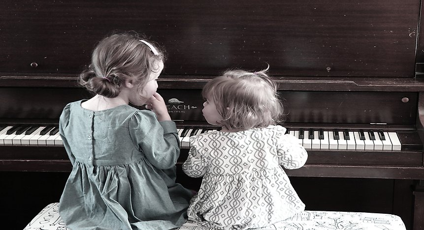 Två barn sitter vid ett piano